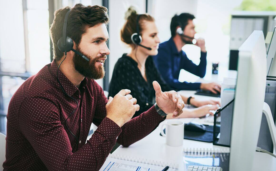 Customer Service Representative with a beard speaking to a customer.