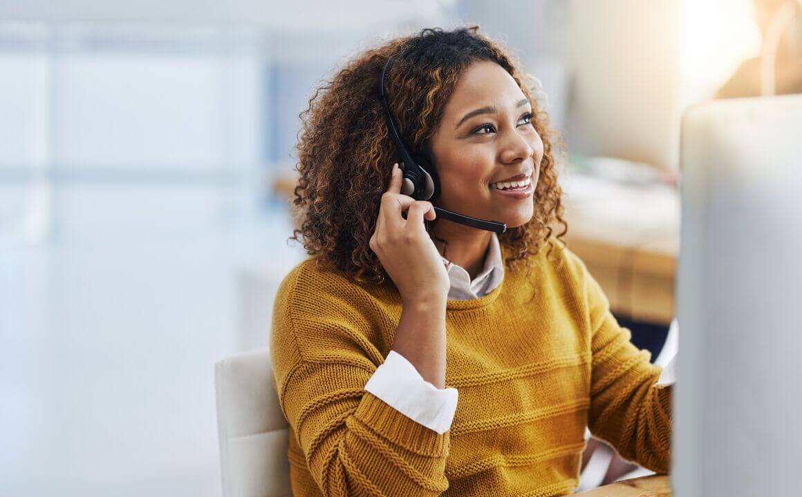 A woman smiles while speaking into a headset