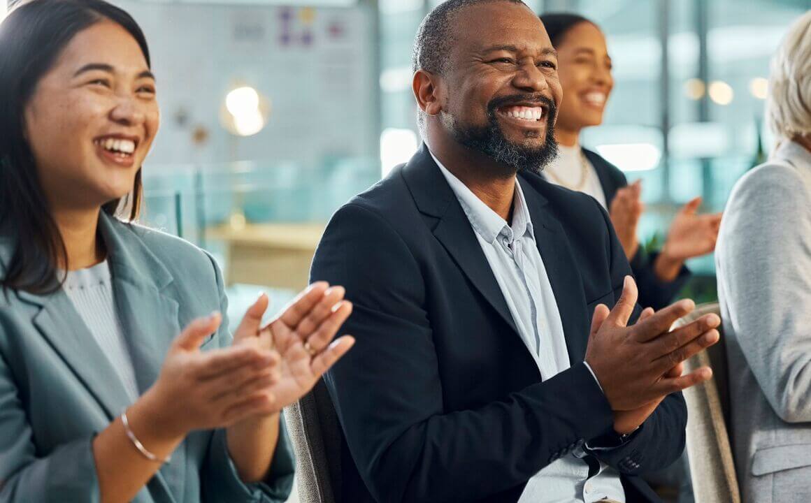 A group of diverse employees smiles and claps