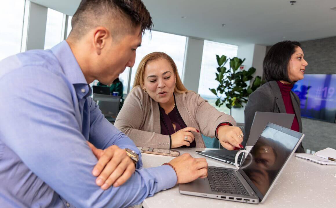 two employees work together around a laptop