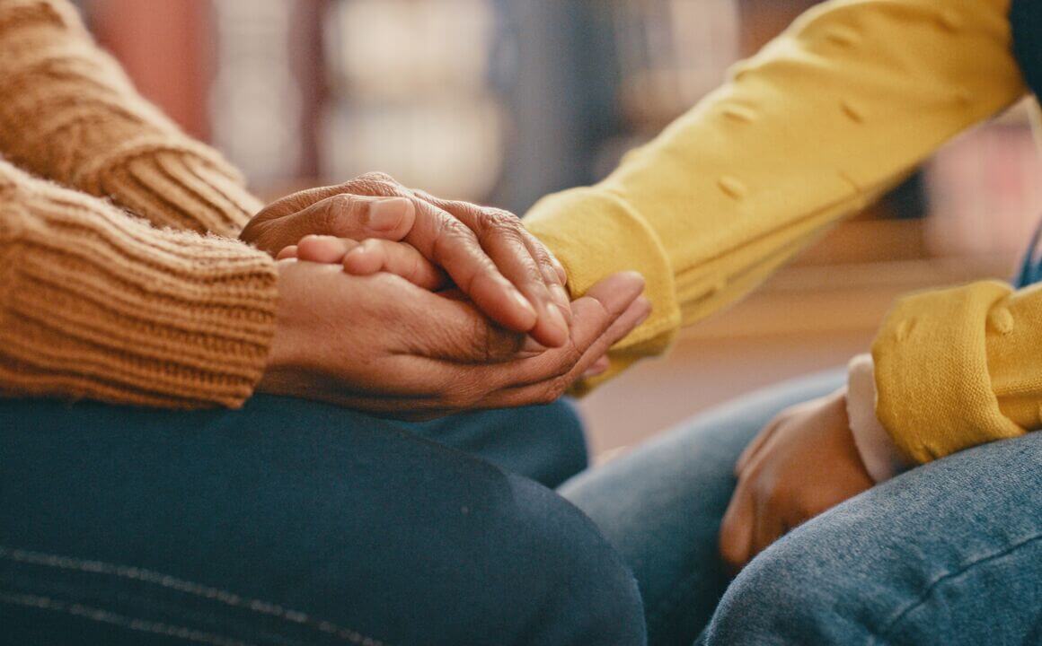 two people hold hands, with only their hands and arms visible