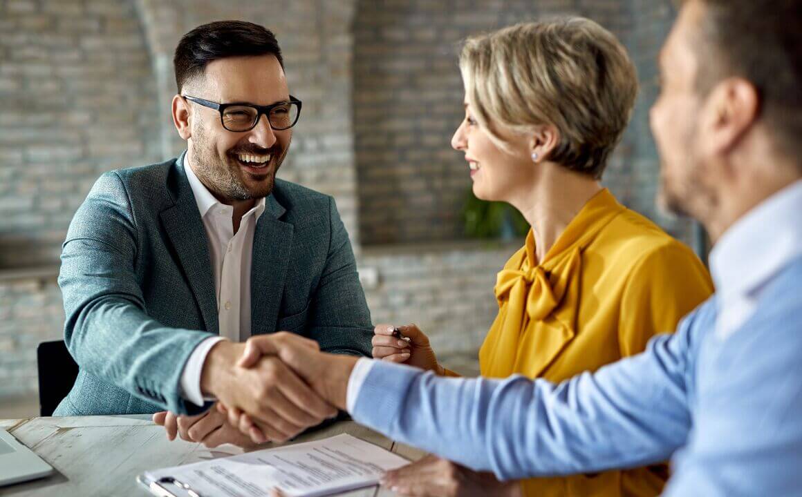 a man in glasses smiles while shaking hands