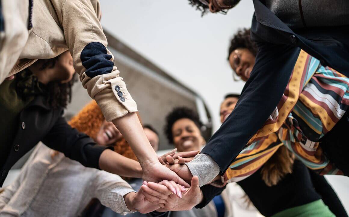 A team of employees stacks their hands together