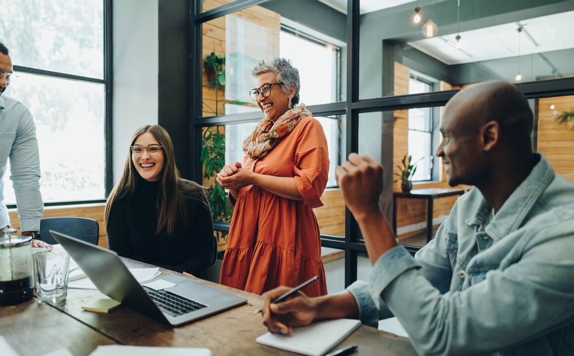 a diverse team laughs in a bright office setting